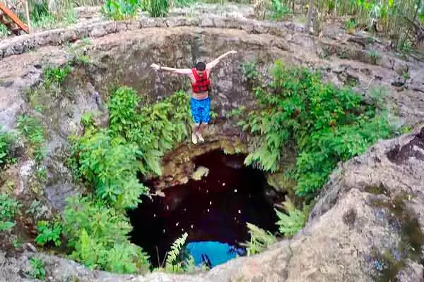 Joven turista saltando al cenote