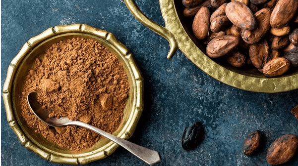 vista superior de un bowl de madera con cacao en polvo y granos de cacao natural